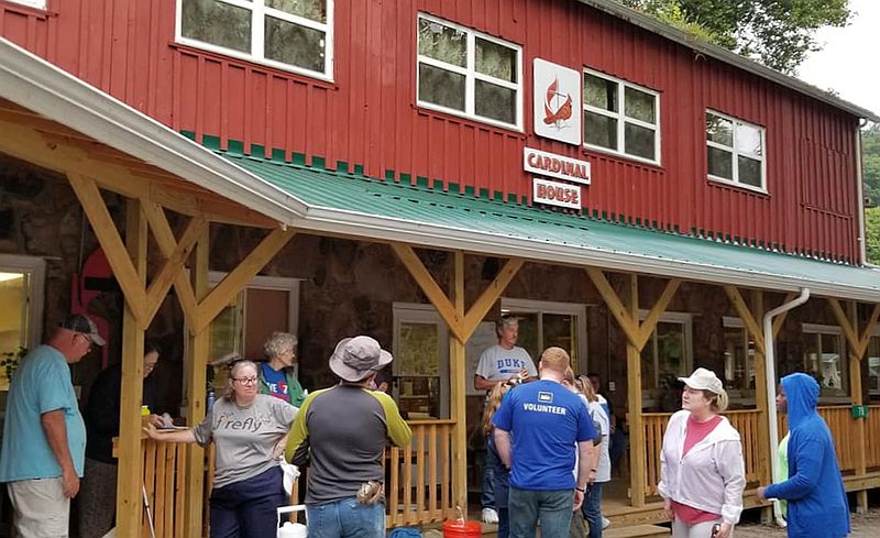 people gather on the porch of a red building