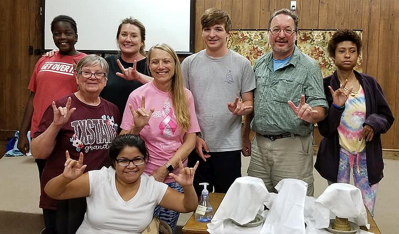 a group signs I Love You around a communion table