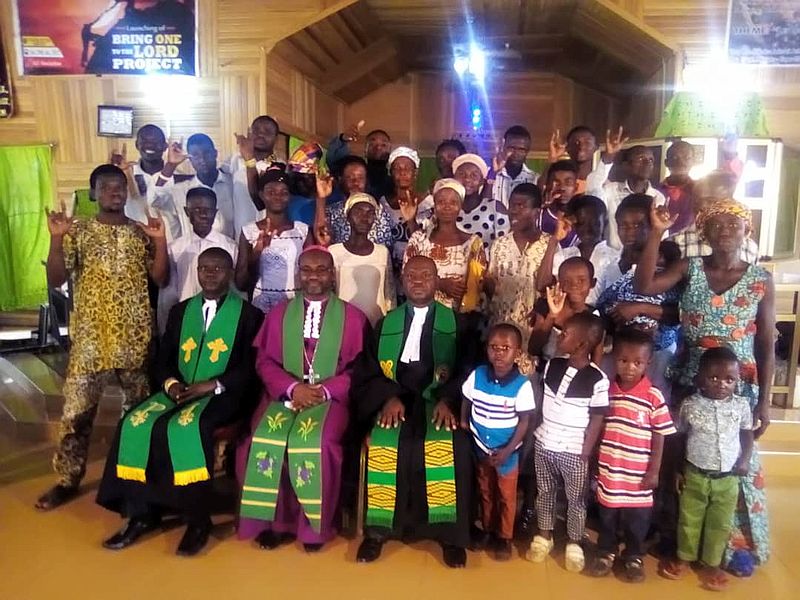 photo or a large group, some signing I Love You, seated in first row are three clergy.