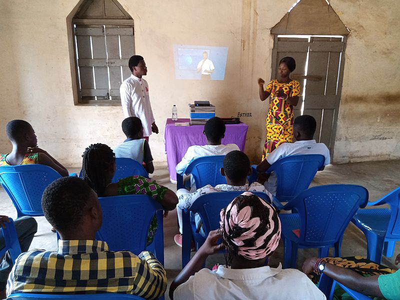 a congregation watches as sign language is projected on the wall.